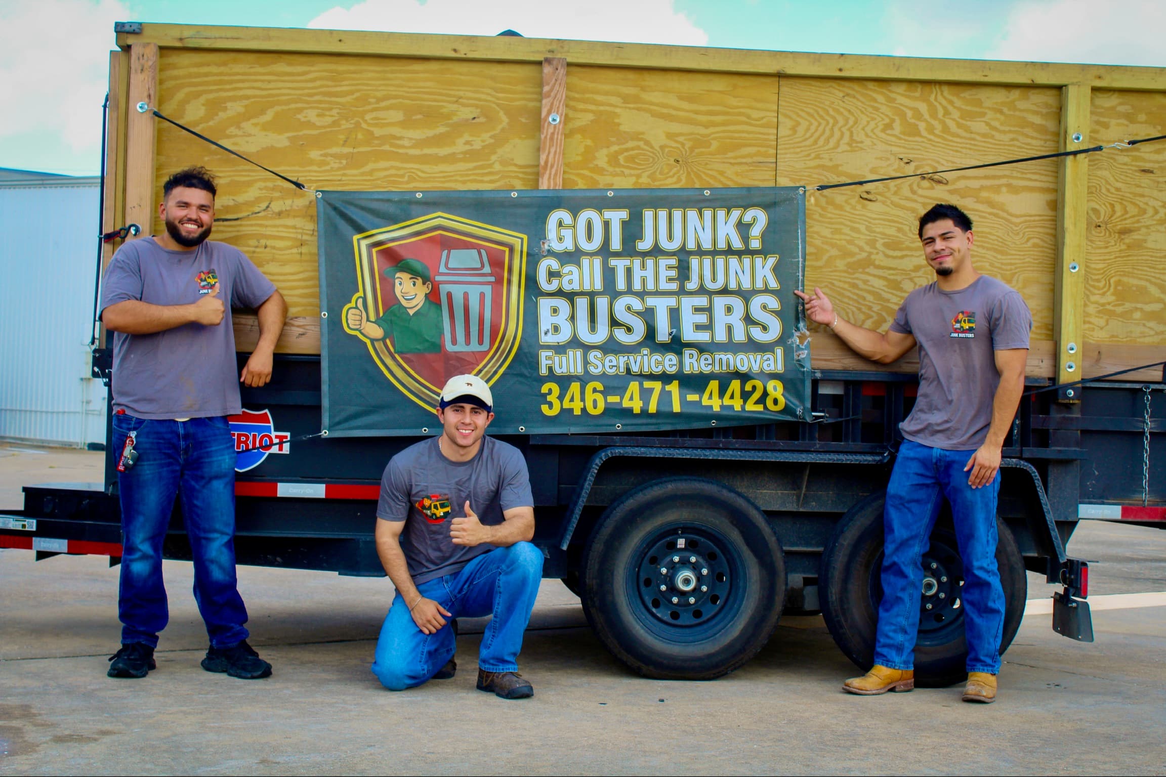 The Junk Busters crew — Jancarlos, Lucas and Aidan — in front of their dump trailer and Got Junk? banner in Houston